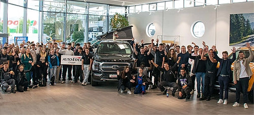 Alle neuen Azubis aufgestellt neben einem Auto