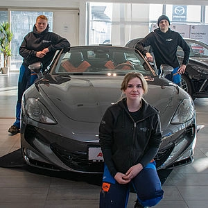 Technische Azubis stehen um Auto